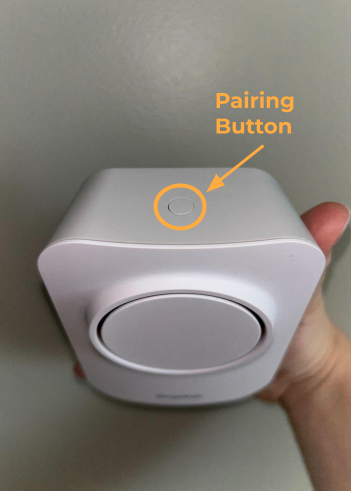 The SimpliSafe® Extra Siren, with a circle highlighting the device's Pairing Button on the top of the device.